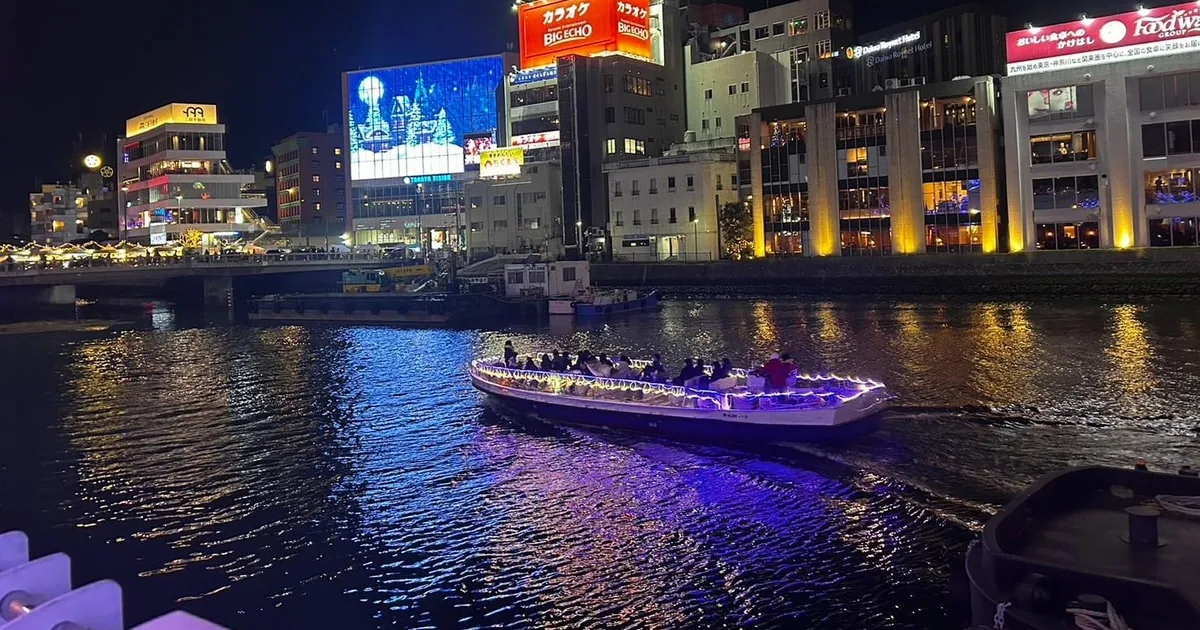 夜の中洲:ネオンのビルを背に、川を進むライトアップされた観光船