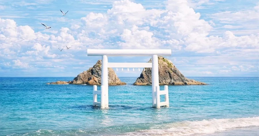 糸島沖、ターコイズ色の海に立つ白い鳥居と、その奥の夫婦岩