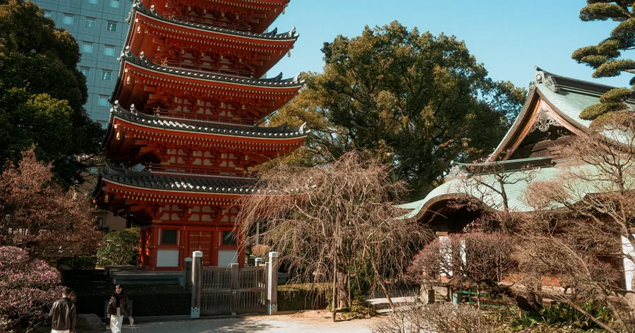 博多旧市街の路地を東長寺の朱色の五重塔へ向かって歩く少人数のグループ